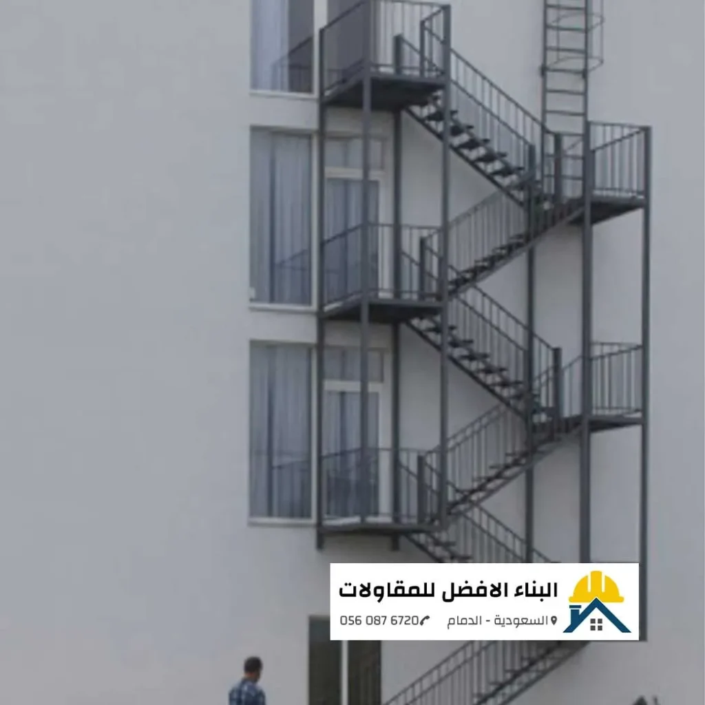 درج حديد خارجي رمادي اللون مخصص لمخارج الطوارئ ومثبت على واجهة مبنى أبيض بالدمام، تنفيذ مؤسسة البناء الأفضل للمقاولات.