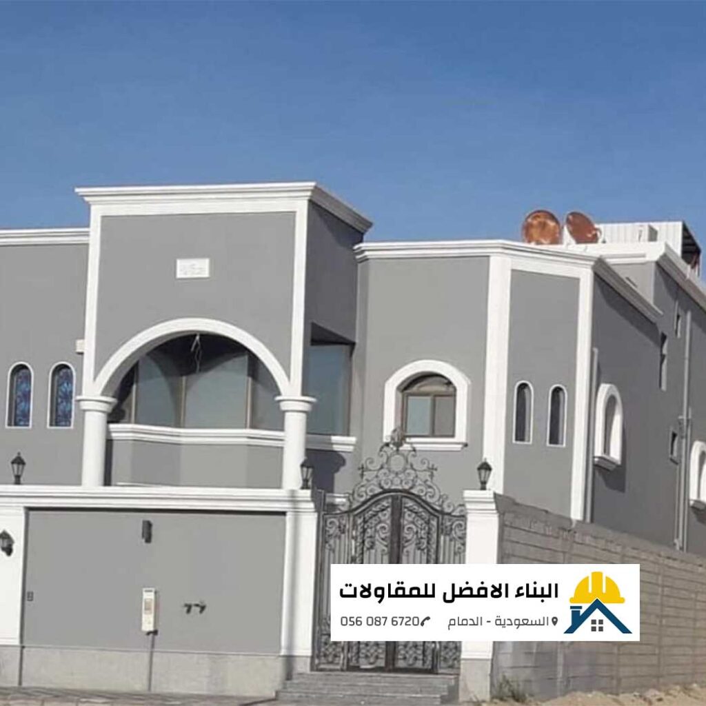 واجهة فيلا طابقين ذات تفاصيل معمارية مدهونة بأصباغ خارجية باللون الرمادي مع تحديد الأقواس والكرانيش والبرامق باللون الأبيض الناصع، وبوابة حديد كلاسيكية سوداء، من تنفيذ مؤسسة البناء الأفضل للمقاولات بالدمام مع الشعار ورقم الاتصال 0560876720.