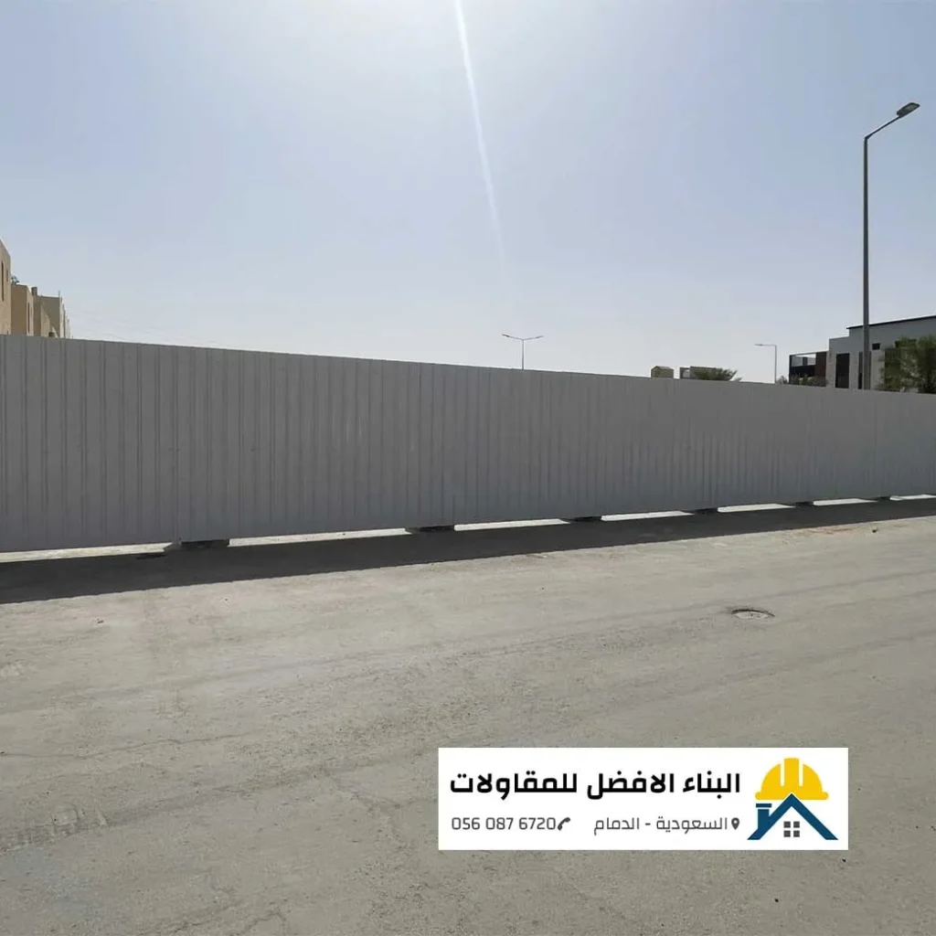سور تحويش ممتد من ألواح الشينكو الأبيض المضلع لتسوير أرض فضاء وموقع عمل على جانب طريق أسفلتي تحت أشعة الشمس، من تنفيذ مؤسسة البناء الأفضل للمقاولات في الدمام 0560876720.