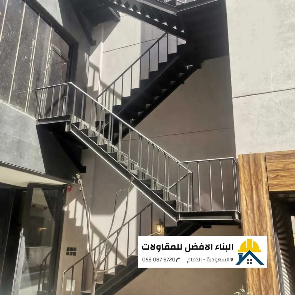درج حديد خارجي أسود بتصميم هندسي عصري ودرابزين معدني آمن مثبت على واجهة مبنى بالدمام، تنفيذ مؤسسة البناء الأفضل للمقاولات.