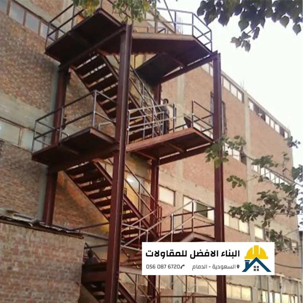 درج حديد خارجي بني اللون مخصص لمخارج الطوارئ ومثبت على واجهة مبنى طابوق بالدمام، تنفيذ مؤسسة البناء الأفضل للمقاولات.